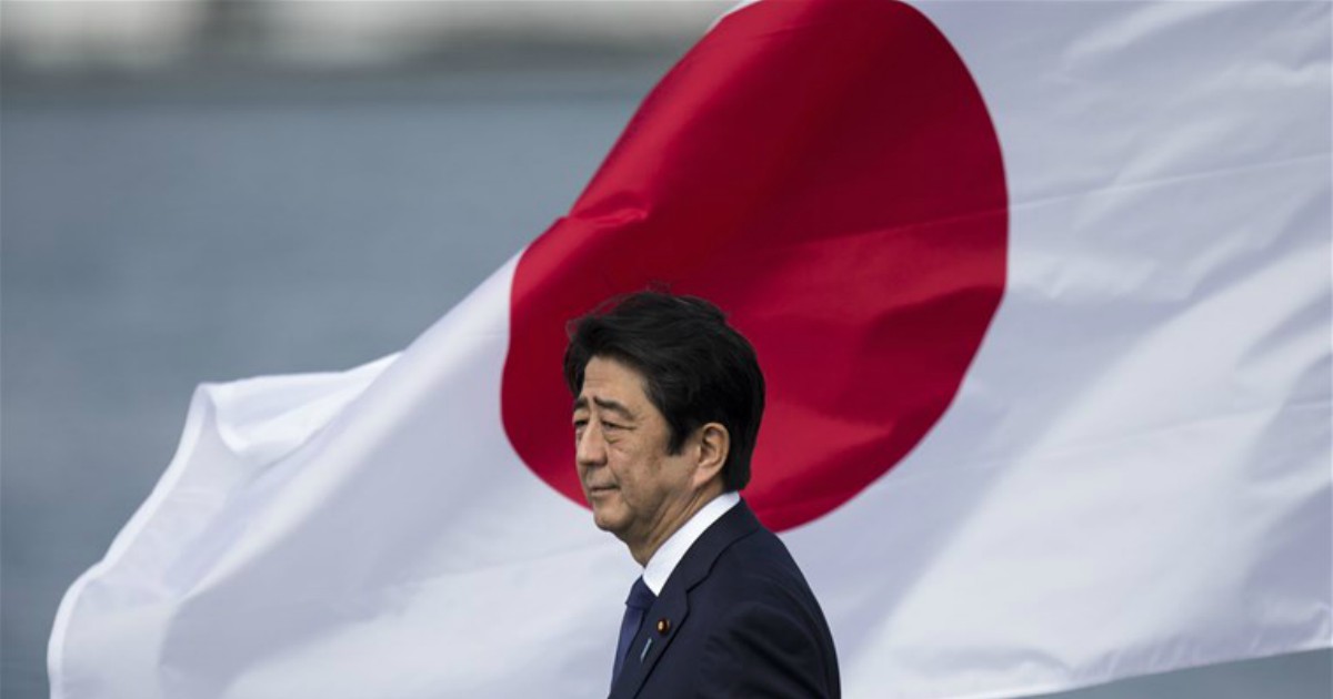 Shinzo Abe, sullo sfondo la bandiera del Giappone